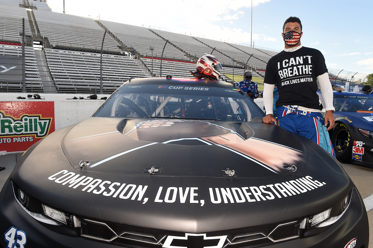 NASCAR driver Bubba Wallace stands next to car