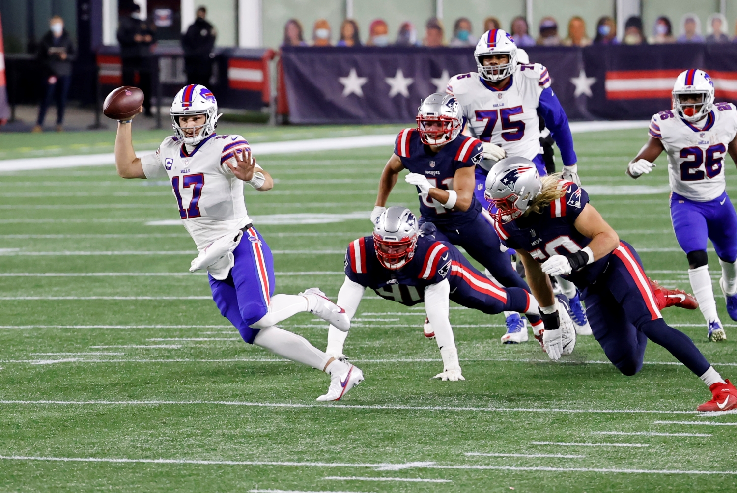 Buffalo Bills QB Josh Allen runs past several Patriots defenders during a game.