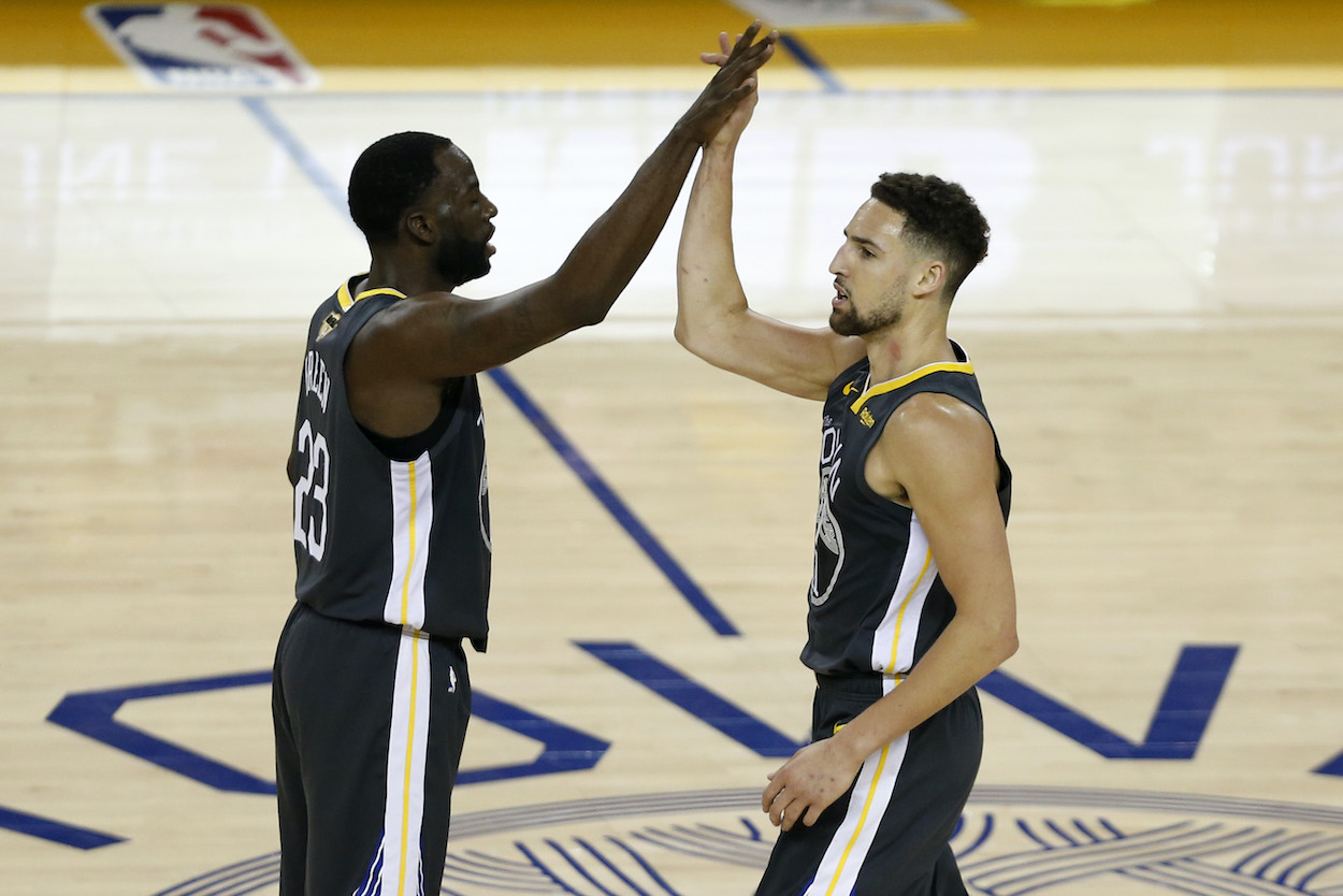 Golden State Warriors teammates Klay Thompson and Draymond Green high-five on the court in 2019.
