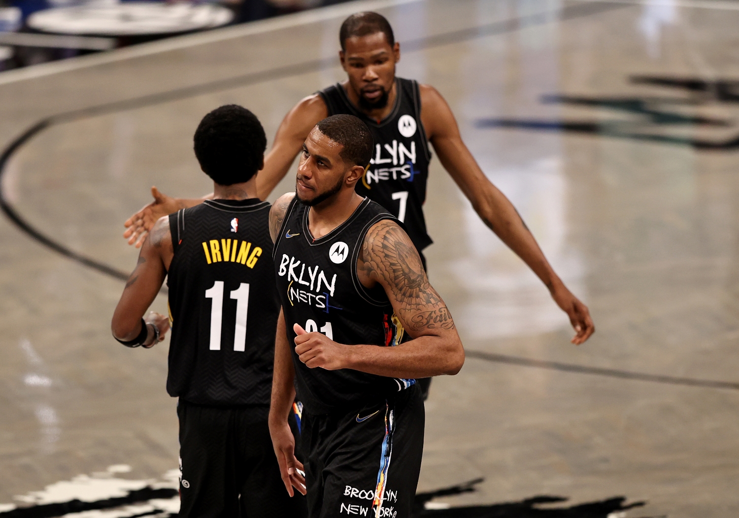 LaMarcus Aldridge walks off the court as Nets teammates Kevin Durant and Kyrie Irving shake hands.