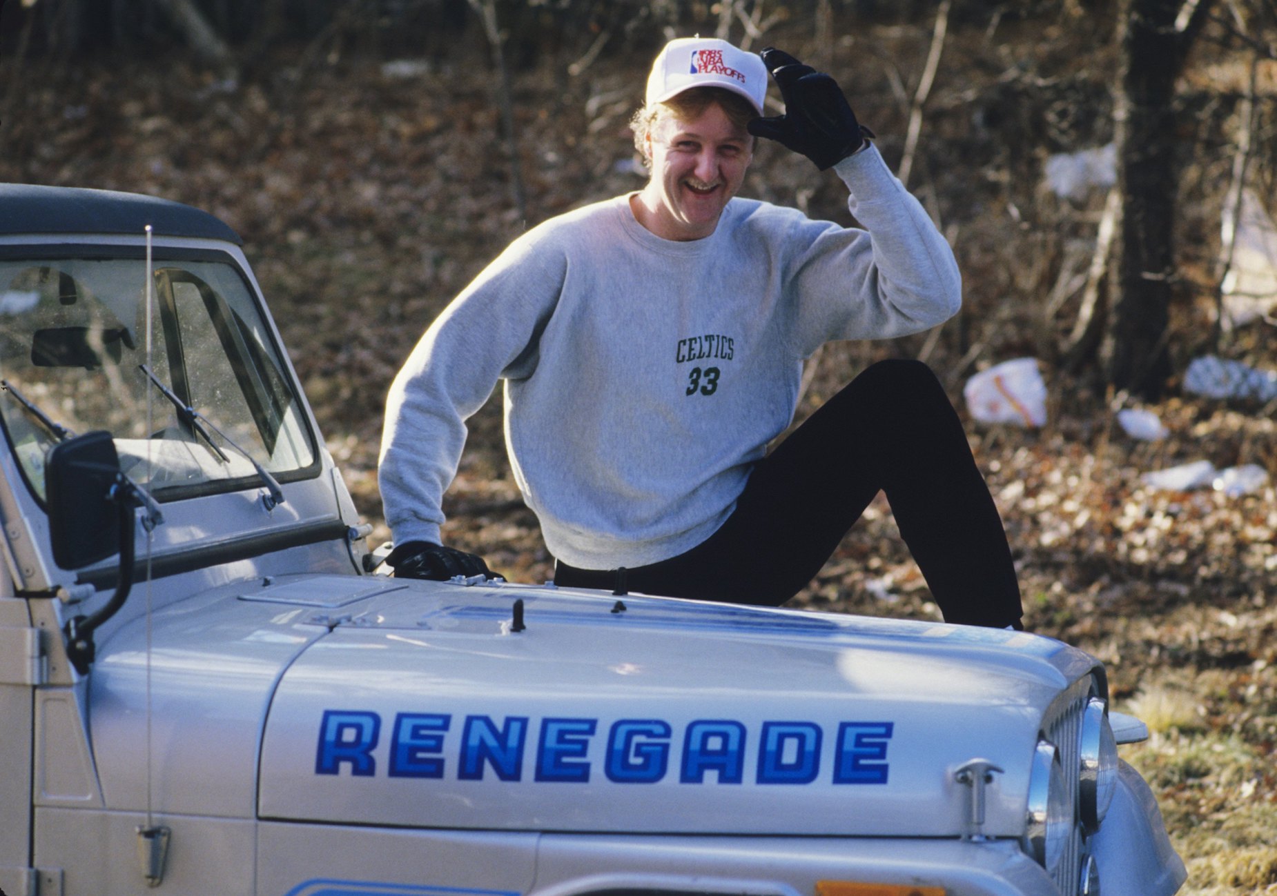 Boston Celtics forward Larry Bird poses next to a Jeep.