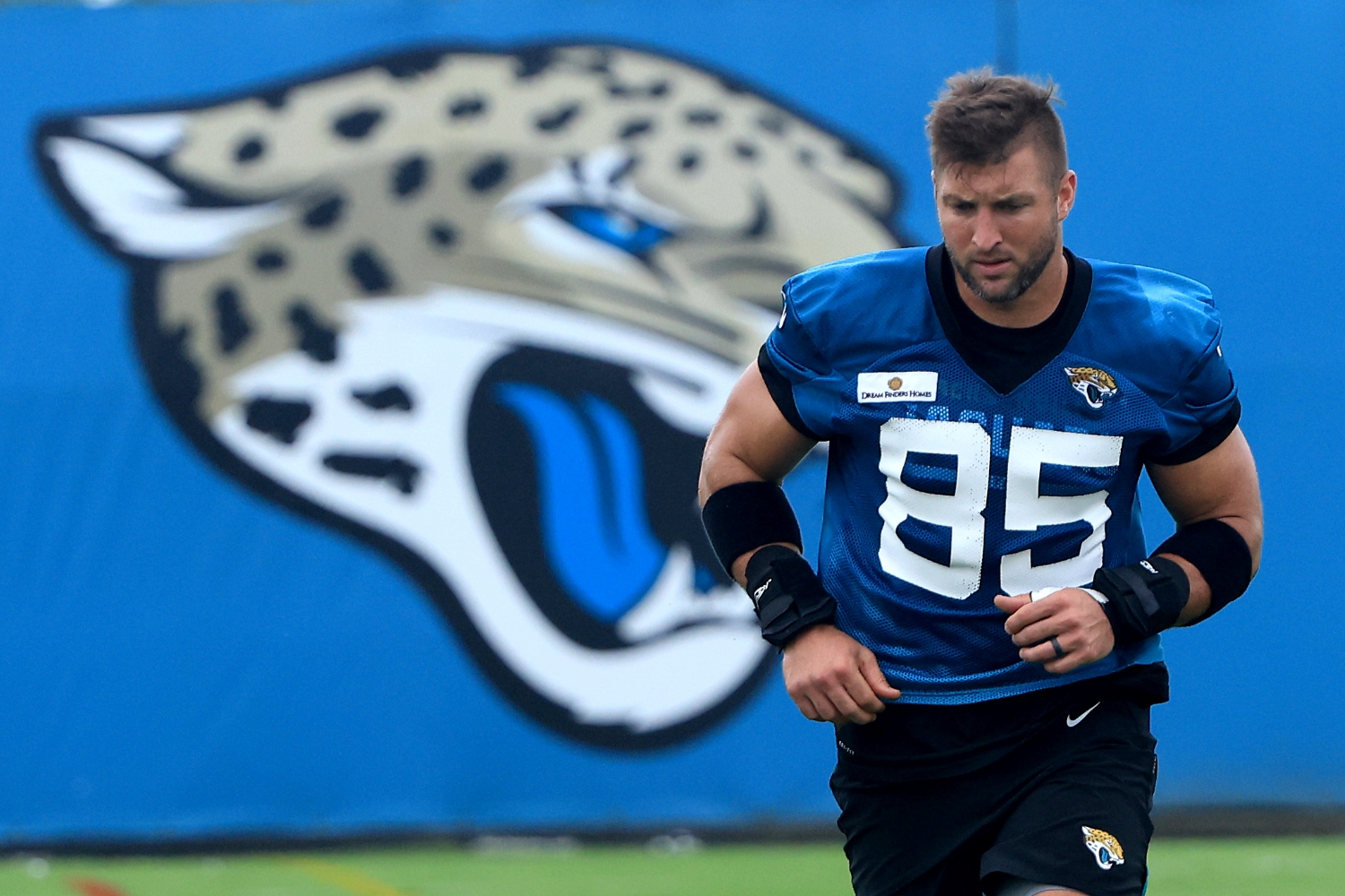 Tim Tebow jogs on the field during Jaguars practice.