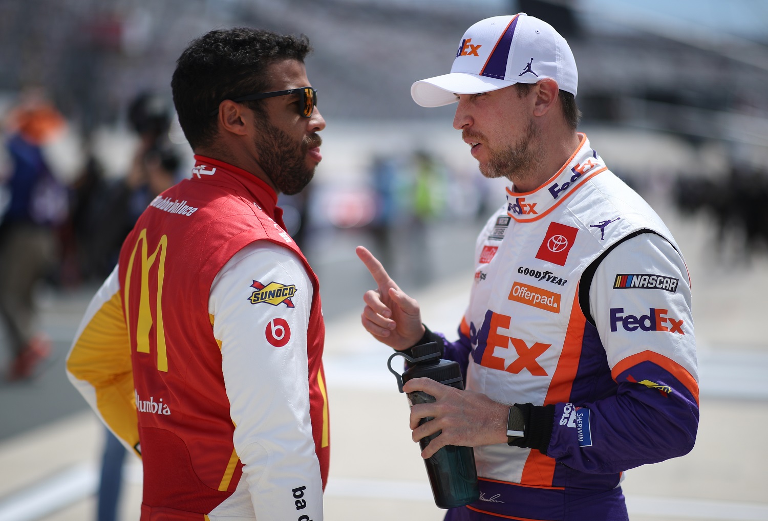 Bubba Wallace, driver of the No. 23 Toyota, and Denny Hamlin, driver of the No. 11 Toyota, talk on the grid during the NASCAR Cup Series Drydene 400 at Dover International Speedway on May 16, 2021 in Dover, Delaware.
