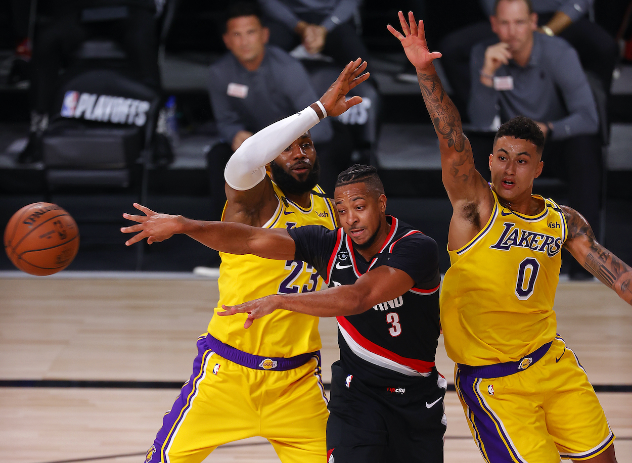 CJ McCollum of the Portland Trail Blazers passes the ball as LeBron James of the Los Angeles Lakers and Kyle Kuzma of the Los Angeles Lakers defend during the second quarter in Game One of the Western Conference First Round during the 2020 NBA Playoffs at AdventHealth Arena at ESPN Wide World Of Sports Complex on August 18, 2020 in Lake Buena Vista, Florida.