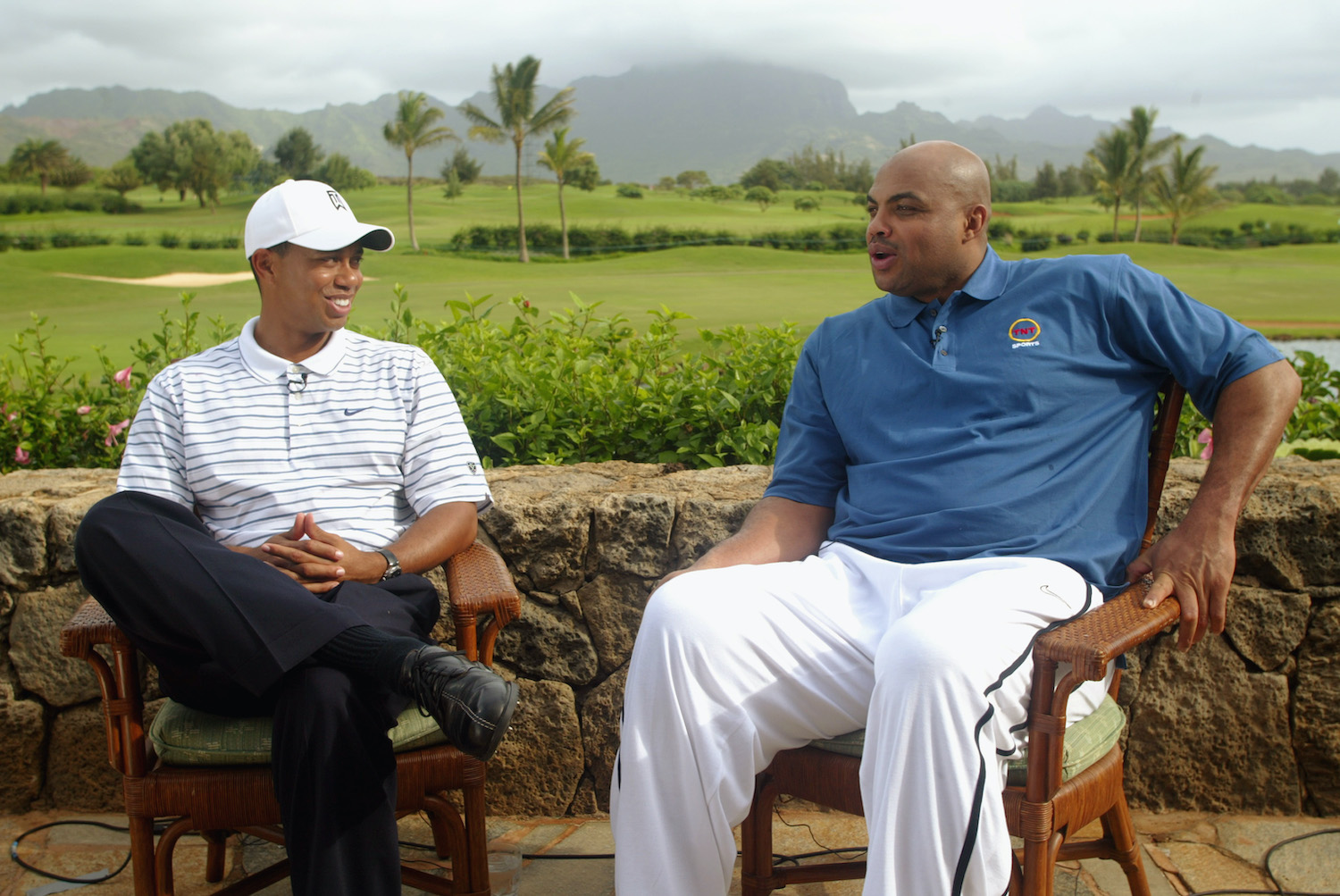 Former NBA star Charles Barkley (R) and pro golfer Tiger Woods (L) sit together in 2002.