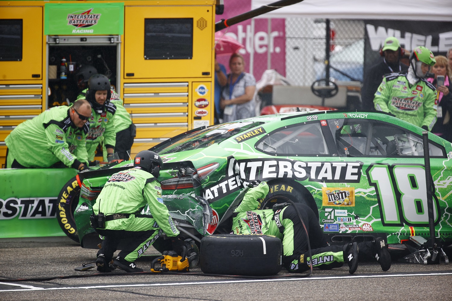 The pit crew works to repair the No. 18 Joe Gibbs Racing Toyota driven by Kyle Busch after an early wreck at New Hampshire Motor Speedway.