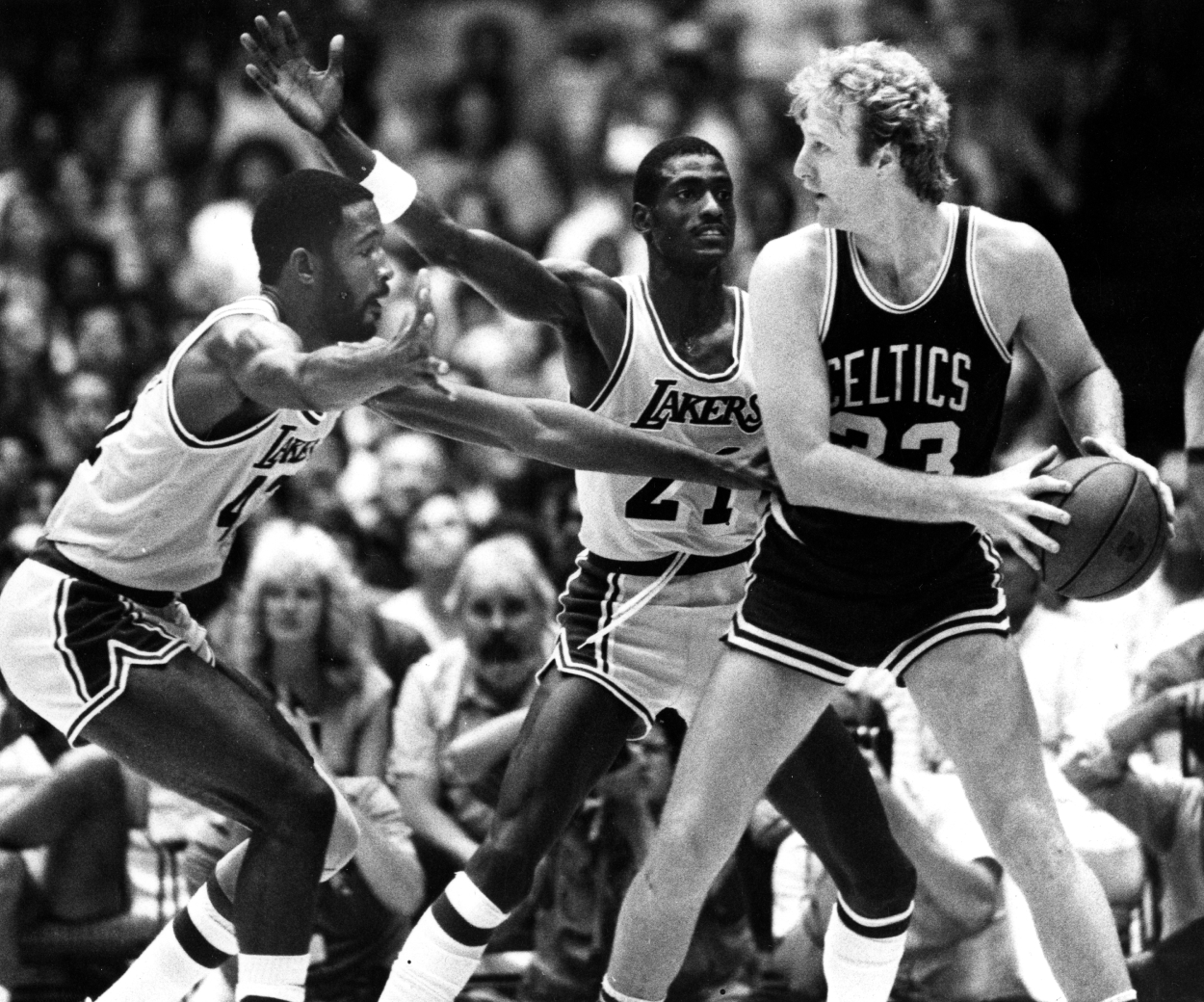 Boston Celtics' Larry Bird is guarded by the Lakers' James Worthy and Michael Cooper.