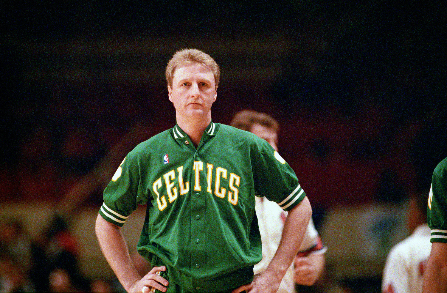 Larry Bird stands on the court in his Boston Celtics warm-up gear.