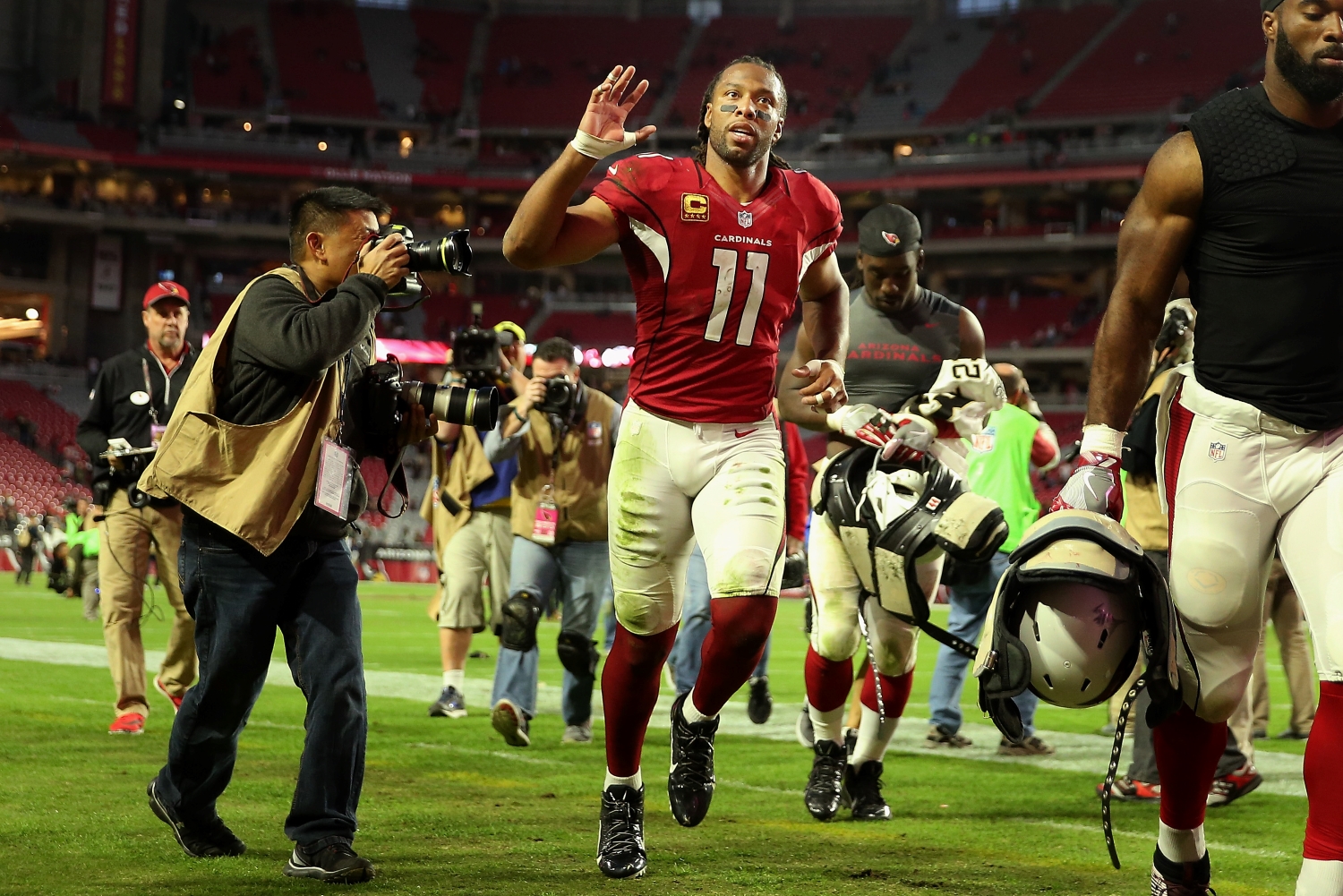 Arizona Cardinals wide receiver Larry Fitzgerald waves to fans as he jogs off the field.