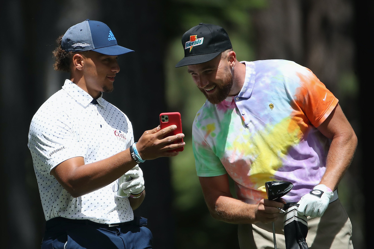 Madden NFL 22 99 Club members Travis Kelce and Patrick Mahomes of the Kansas City Chiefs look at a cell phone as they wait to tee off during round one of the American Century Championship at Edgewood Tahoe South golf course on July 10, 2020 in Lake Tahoe, Nevada.