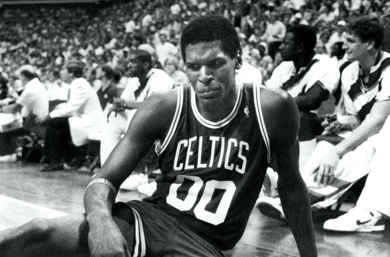 Robert Parish sits on the floor during a Boston Celtics game.