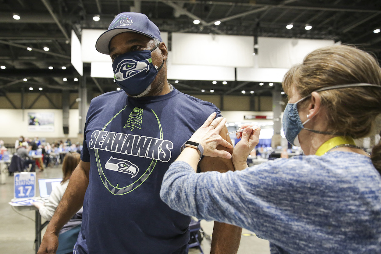 Cleveland Hughes wears Seattle Seahawks gear as he gets the Pfizer Covid-19 vaccine from Andrea Barnett during opening day of the Community Vaccination Site, a collaboration between the City of Seattle, First &Goal Inc., and Swedish Health Services at the Lumen Field Event Center in Seattle, Washington on March 13, 2021. Teams in the league are trying to move up the NFL rankings for vaccinations and hit the 85% threshold.