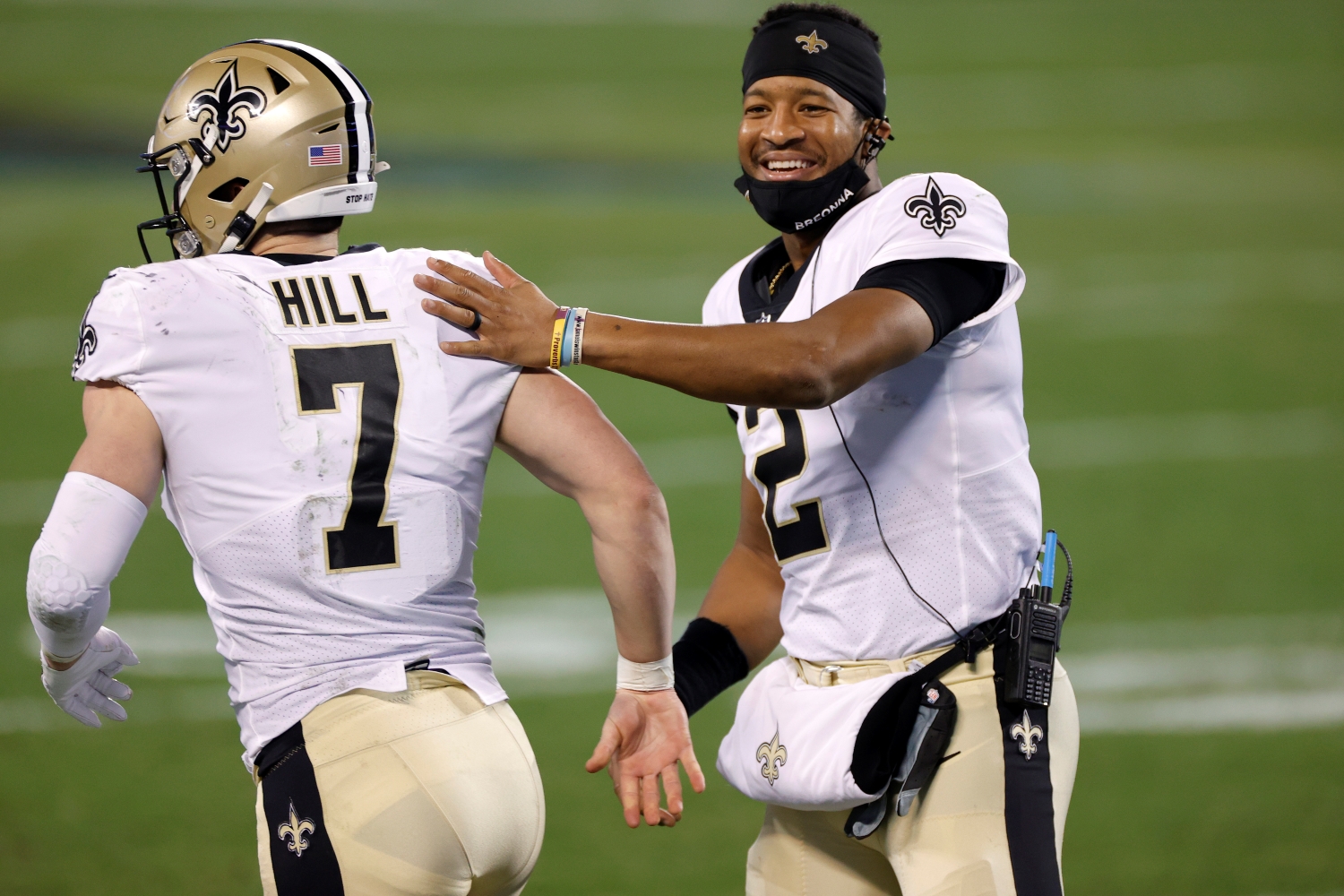 New Orleans Saints quarterback Jameis Winston taps teammate Taysom Hill on the back as he jogs onto the field.