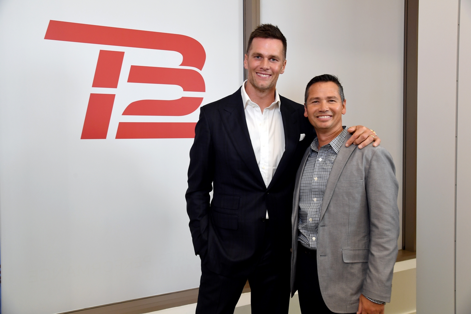 Tom Brady stands next to longtime trainer Alex Guerrero at a TB12 event.