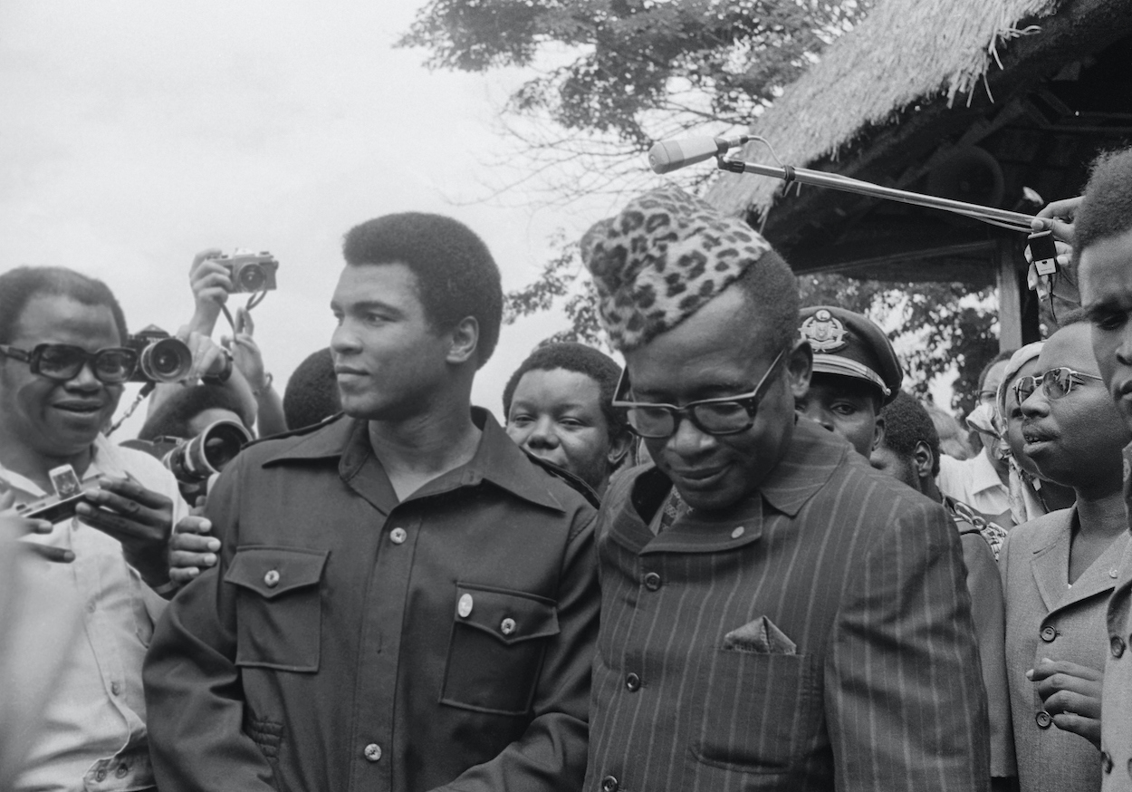 Zaire President Mobutu Sese Seko (right) shows his elaborate walking stick to heavyweight challenger Muhammed Ali during a stroll around the gardens of the presidential palace here Oct. 28th. Ali seeks to regain the heavyweight title in bout against George Foreman here Oct. 30th.