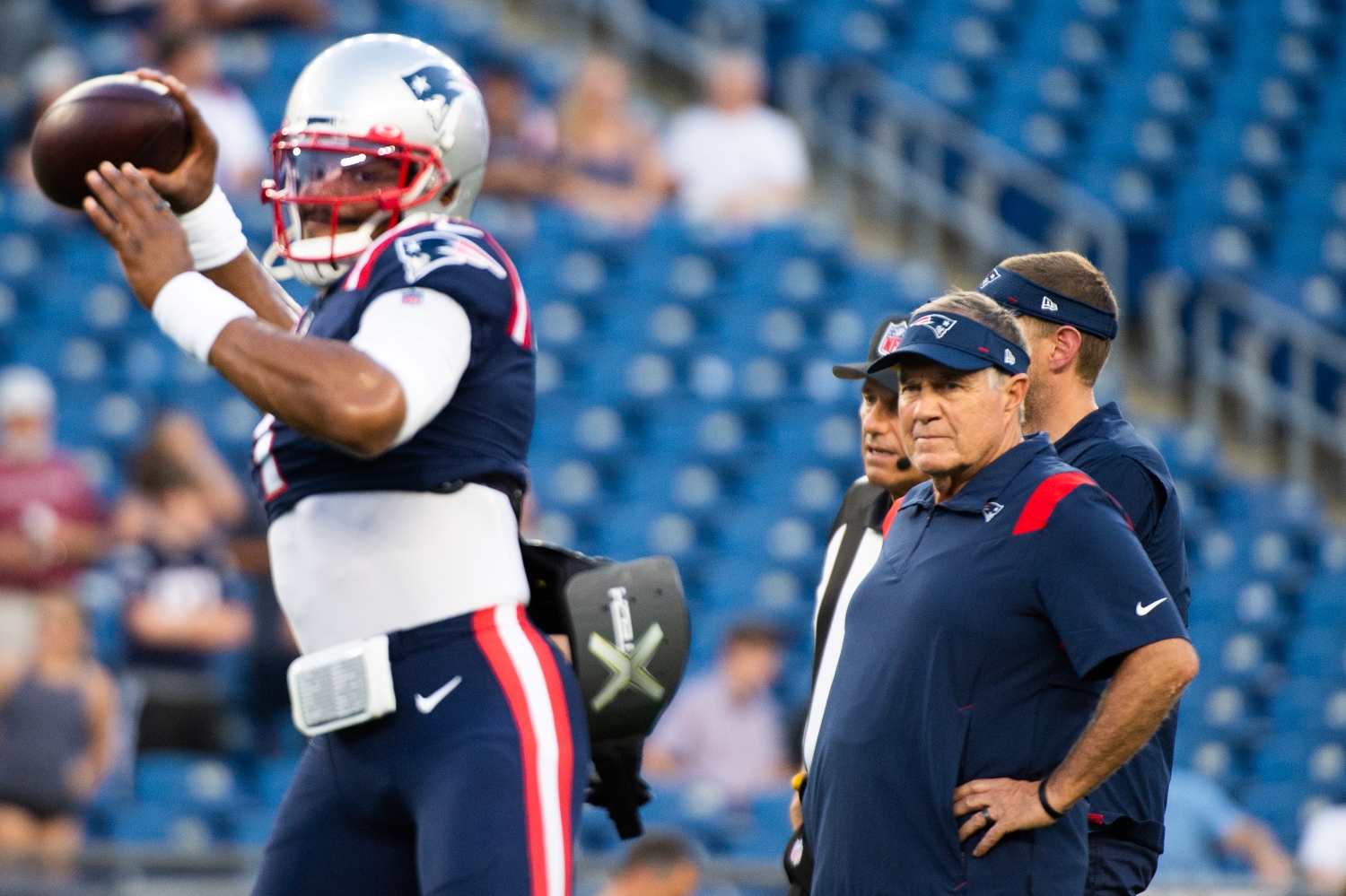 New England Patriots head coach Bill Belichick watches quarterback Cam Newton warm up before a game.