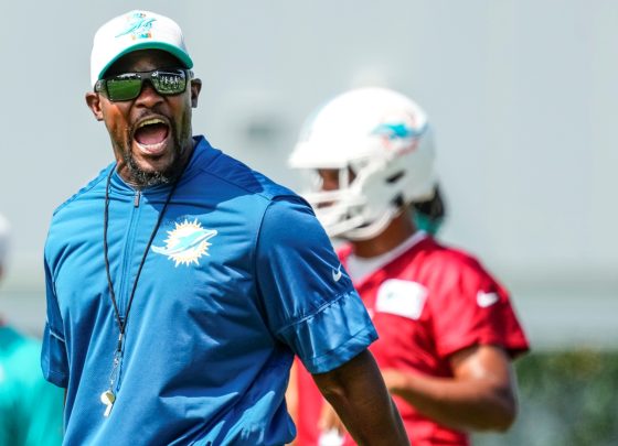 Miami Dolphins head coach Brian Flores giving instructions for practice drills during training camp as Tua Tagovailoa stands in the background.