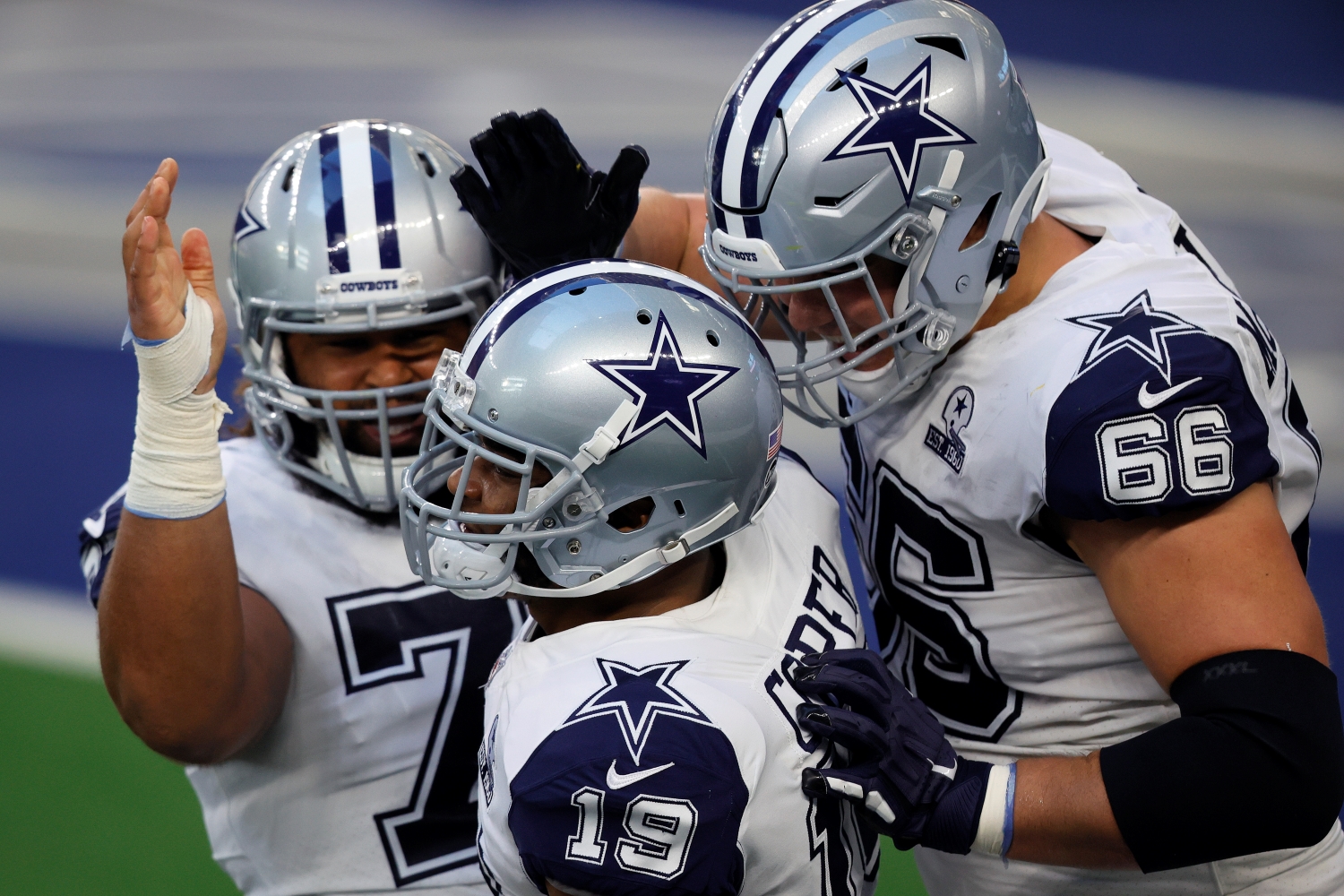 Dallas Cowboys teammates Joe Looney, Amari Cooper, and Connor McGovern celebrate scoring a touchdown.
