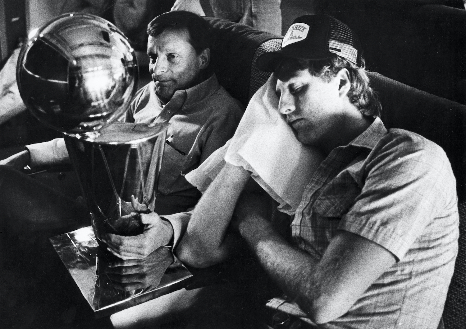 Larry Bird sleeps next to the Larry O'Brien Trophy on the Boston Celtics flight.