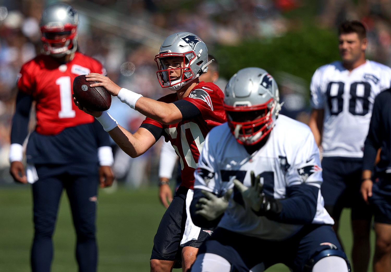 New England Patriots rookie quarterback Mac Jones takes a snap in practice while Cam Newton watches.