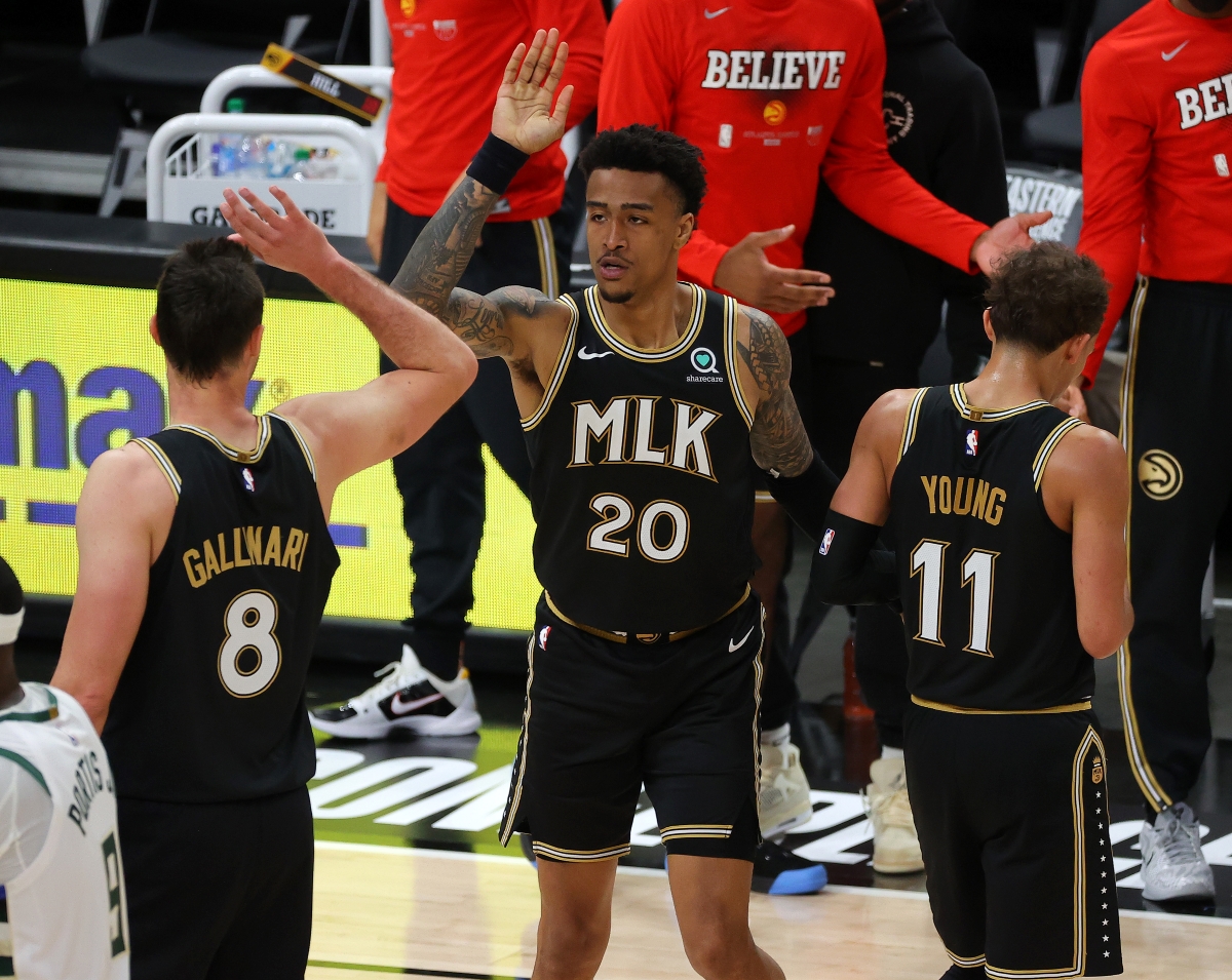 John Collins celebrates with teammates during a game against the Milwaukee Bucks.