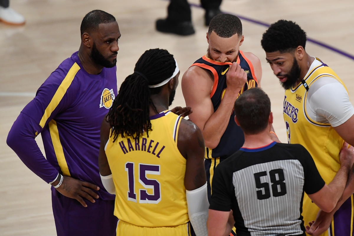 Anthony Davis, LeBron James, and Montrezl Harrell of the Los Angeles Lakers talk with Steph Curry of the Golden State Warriors during a game.