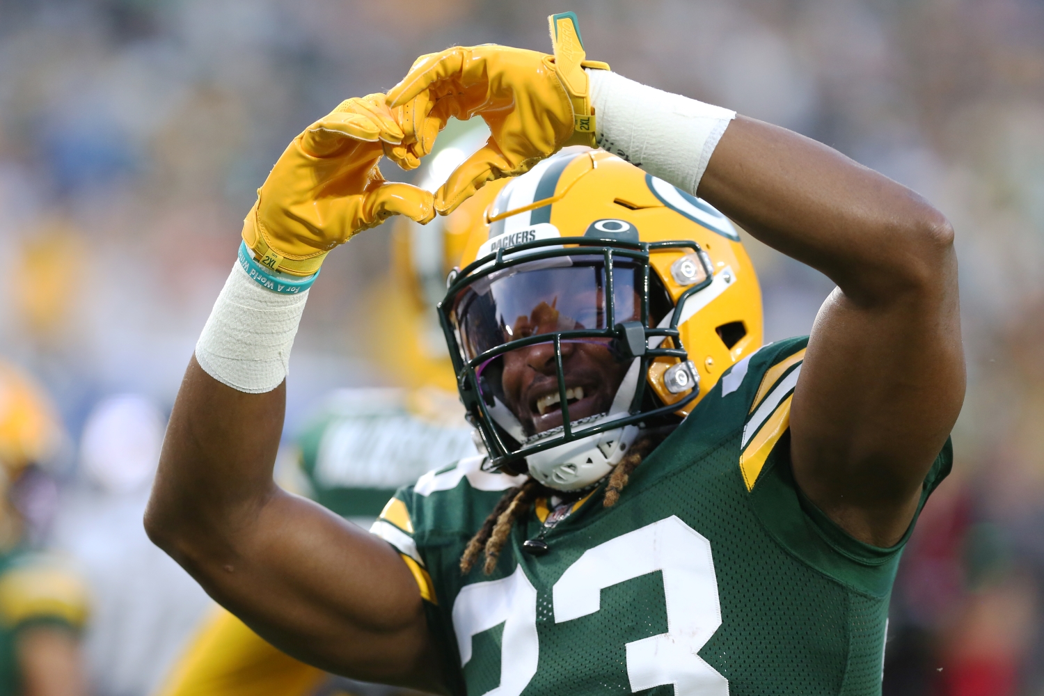 Aaron Jones makes a heart sign for a fan prior to a game between the Green Bay Packers and the Detroit Lions.