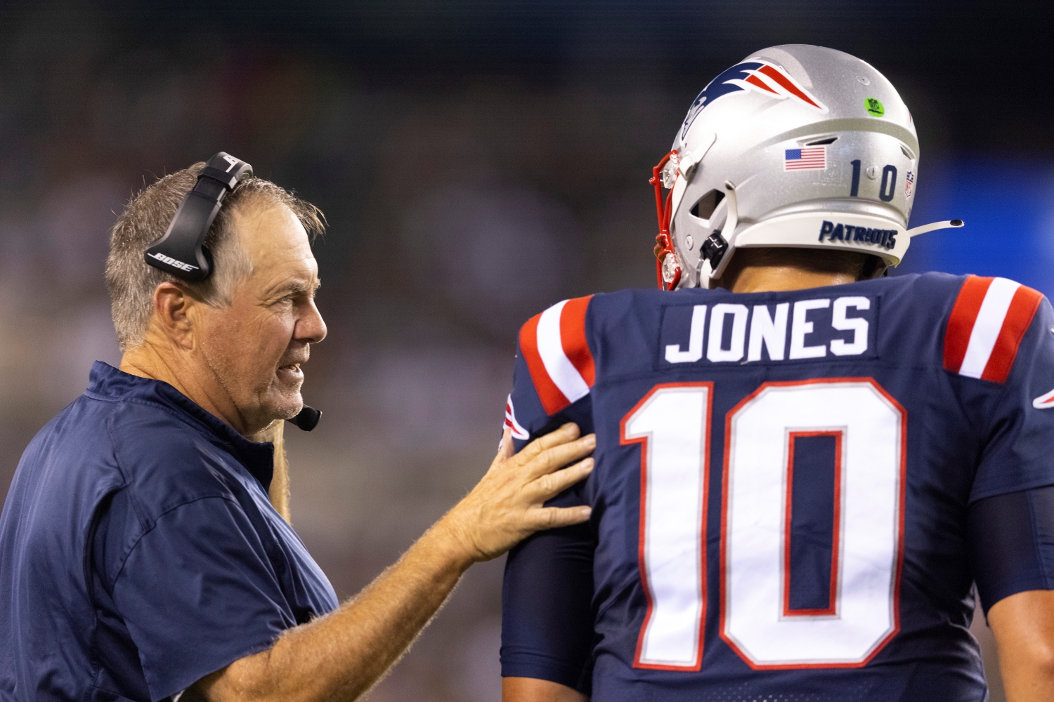 New England Patriots head coach Bill Belichick speaks to Mac Jones during a preseason game.