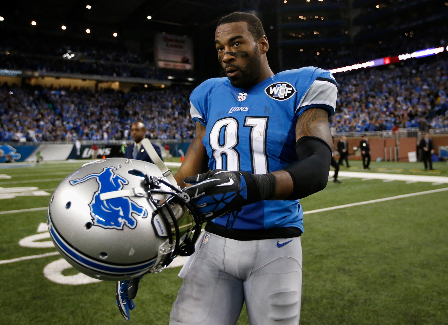 Detroit Lions wide receiver Calvin Johnson walks with his helmet as he exits the field.