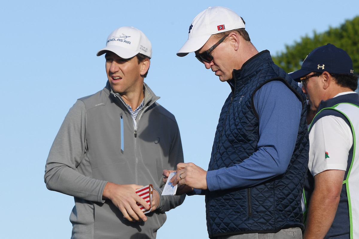 Former NFL players Peyton Manning and Eli Manning look on from the 11th tee of a golf course