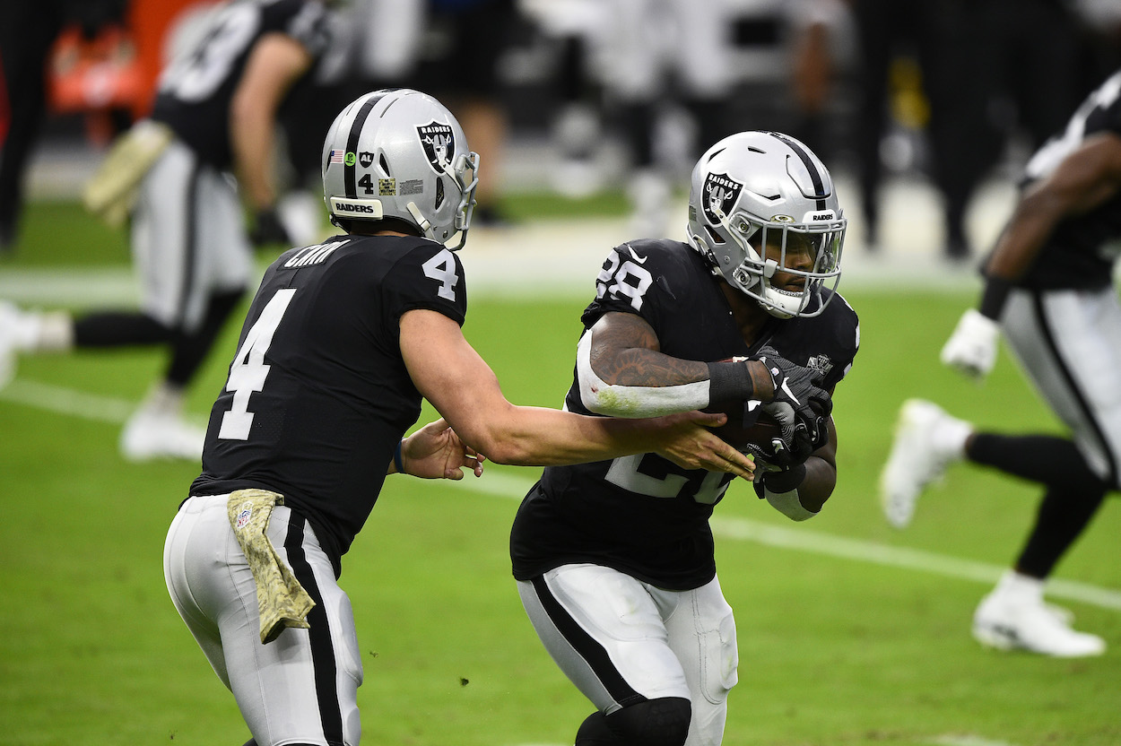 Derek Carr handing the ball off to Josh Jacobs.