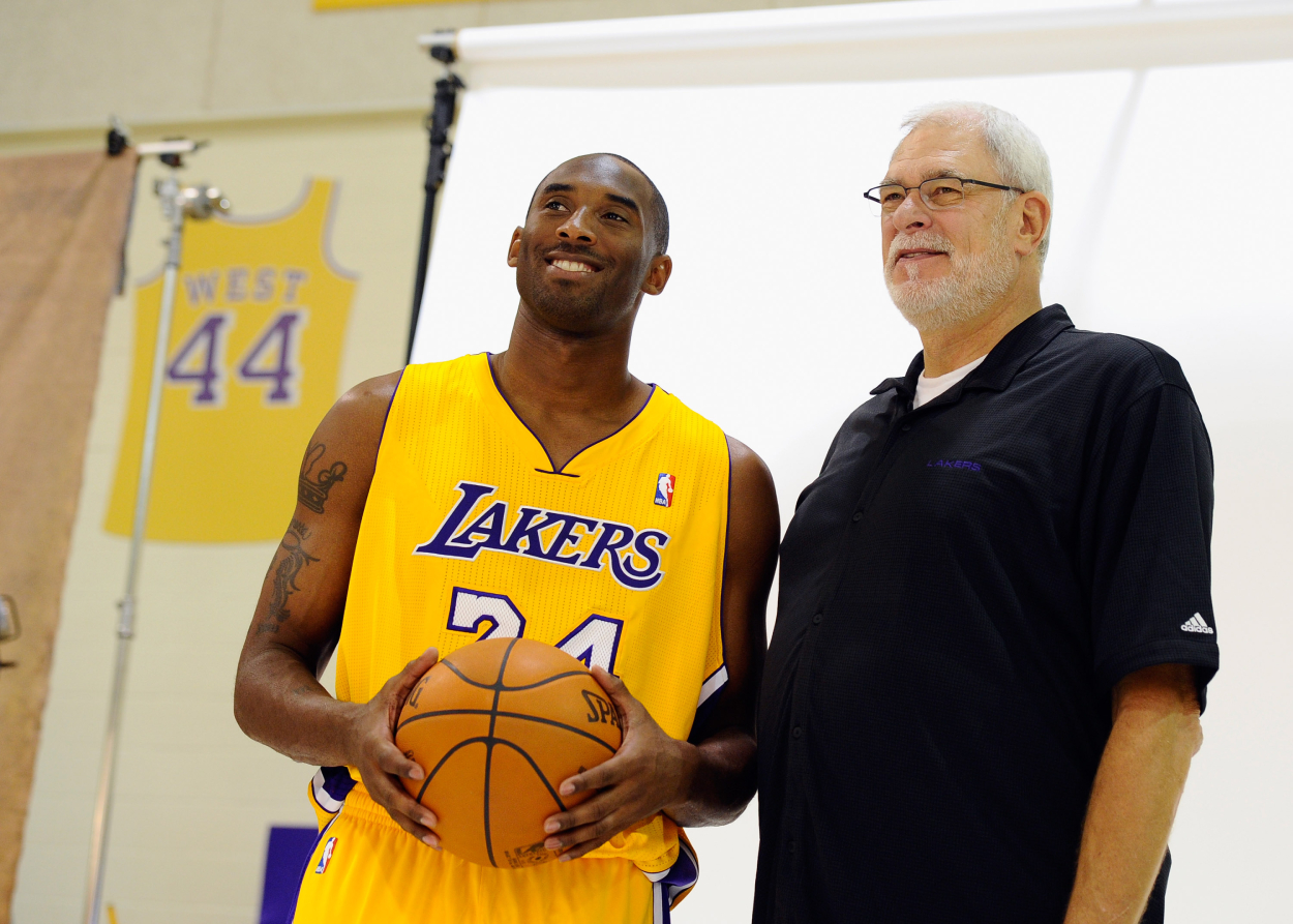 Kobe Bryant holds a basketball while standing next to Phil Jackson during a Lakers media day in 2010