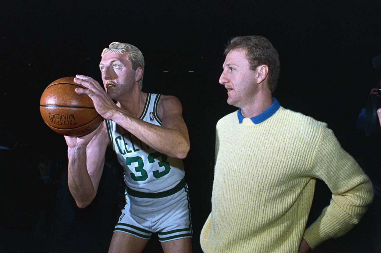Boston Celtics' star Larry Bird poses beside a life-size wooden sculpture of himself.