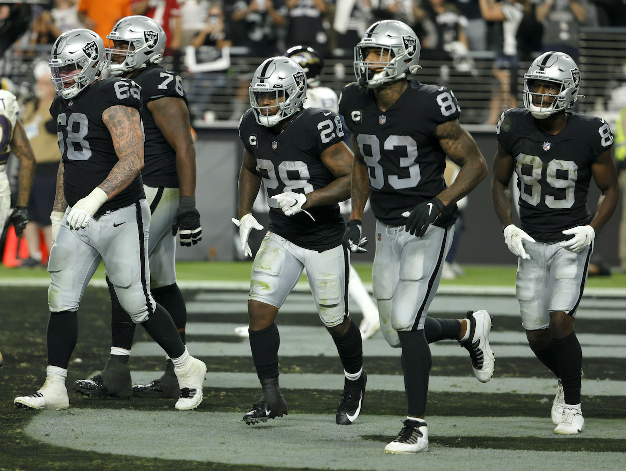 Las Vegas Raiders running back Josh Jacobs (No. 28), tight end Darren Waller (No. 83), and teammates walk off the field after Jacobs scored a 15-yard touchdown against the Baltimore Ravens during their game at Allegiant Stadium on September 13, 2021 in Las Vegas, Nevada. The Raiders defeated the Ravens 33-27 in overtime.