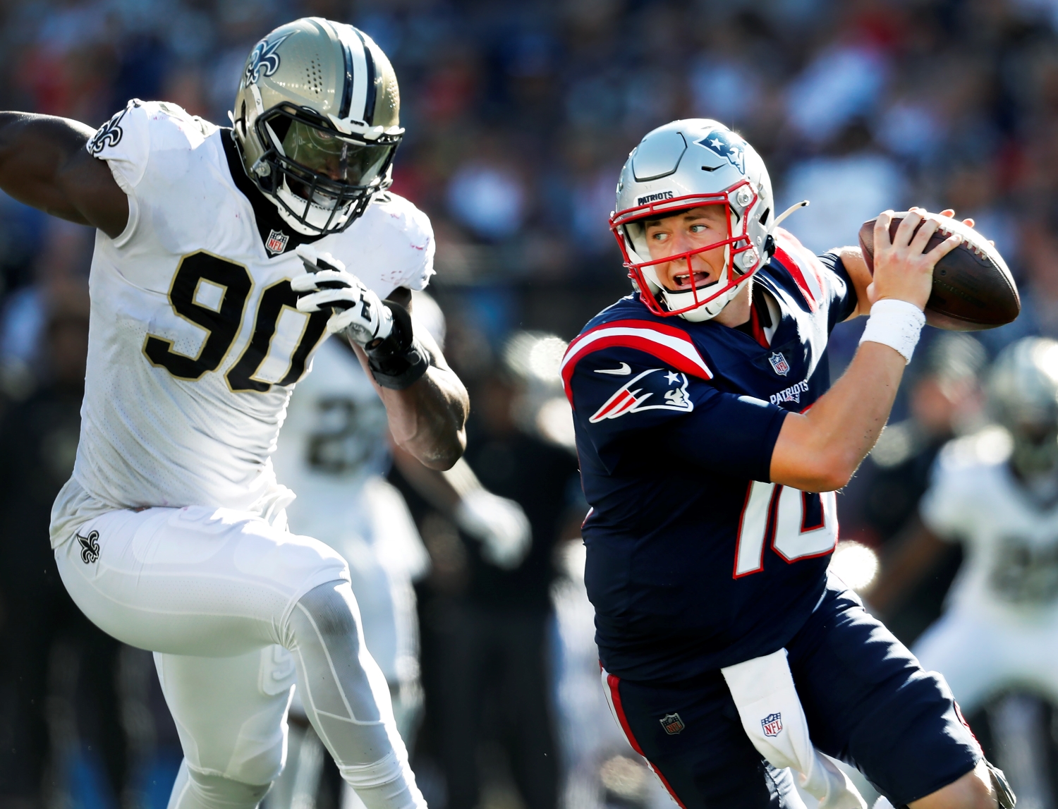 New England Patriots quarterback Mac Jones is pursued by Saints defensive end Tanoh Kpassagnon.
