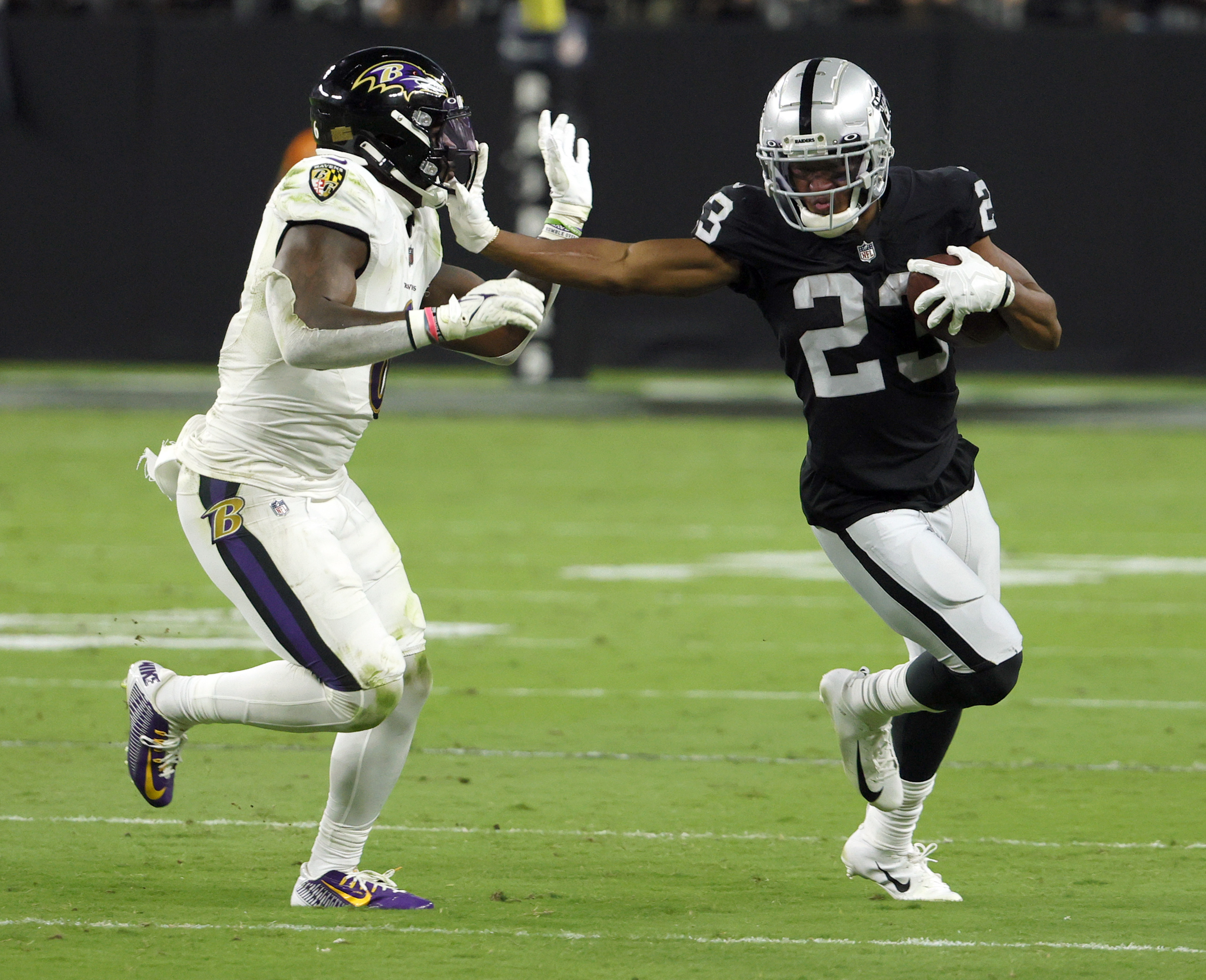 Baltimore Ravens linebacker Patrick Queen gets stiff-armed by Raiders running back Kenyan Drake