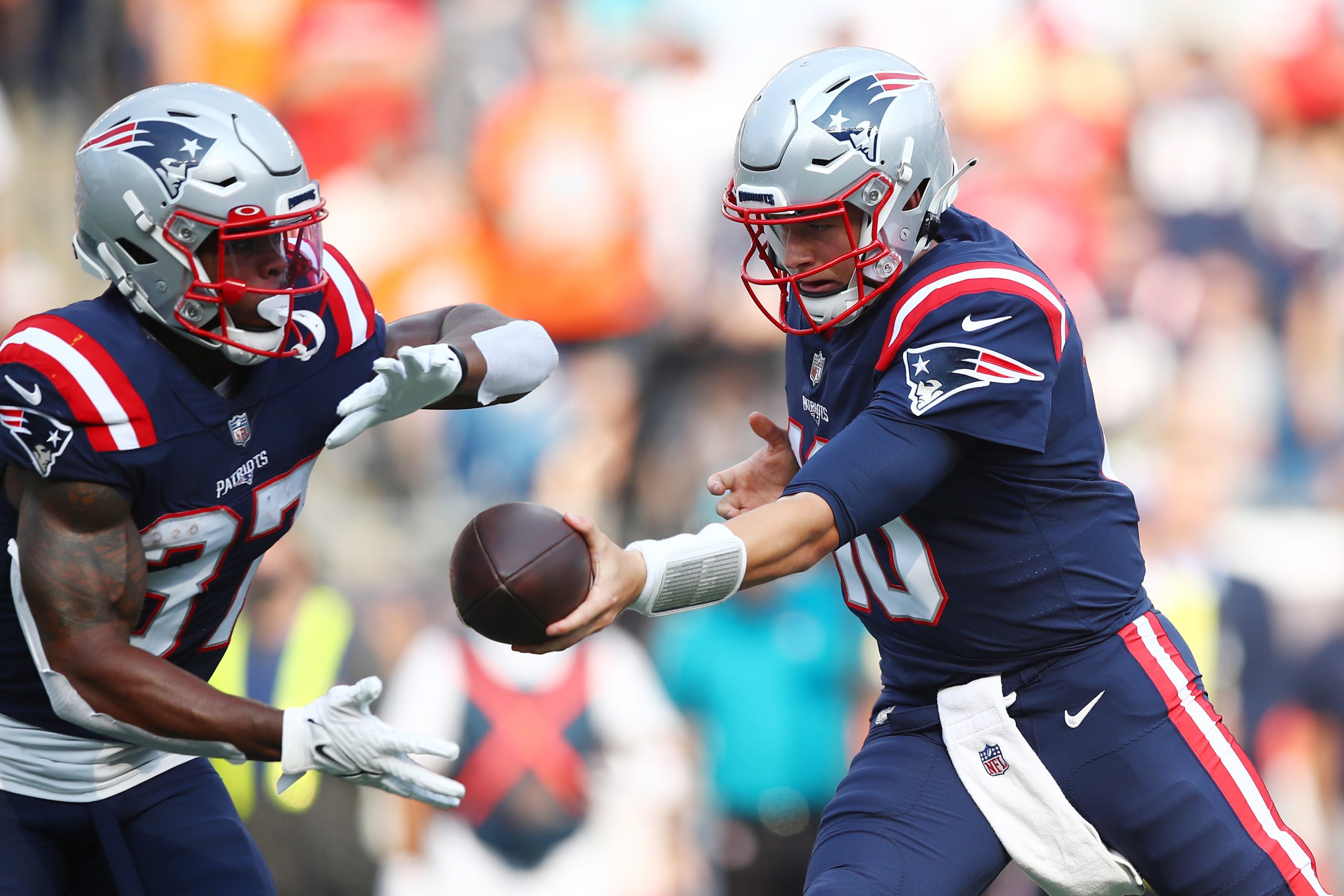 Mac Jones of the New England Patriots looks to hand the ball off to Damien Harris during the first half against the Miami Dolphins.