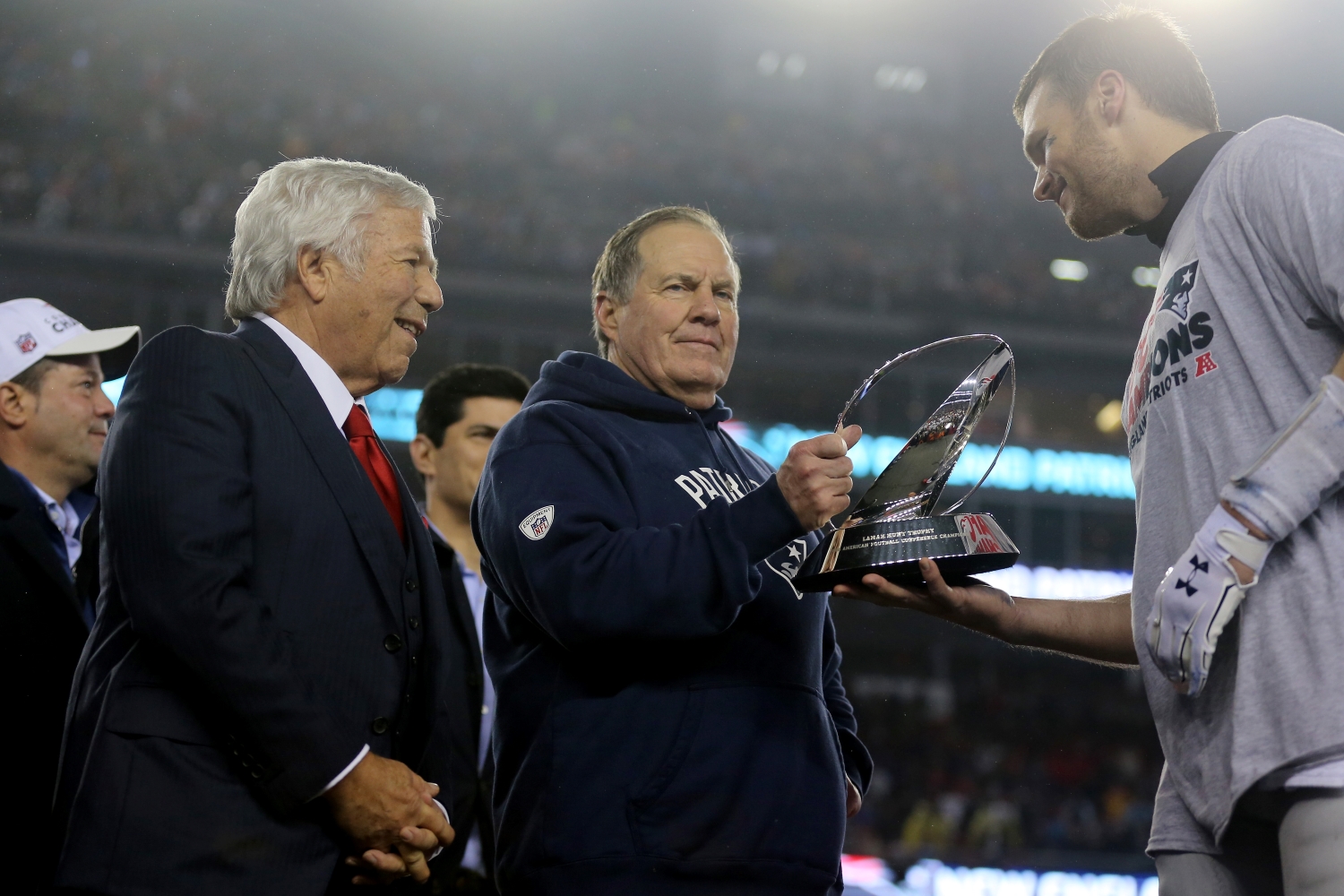 Tom Brady hands the Lamar Hunt Trophy to Bill Belichick as New England Patriots owner Robert Kraft watches.
