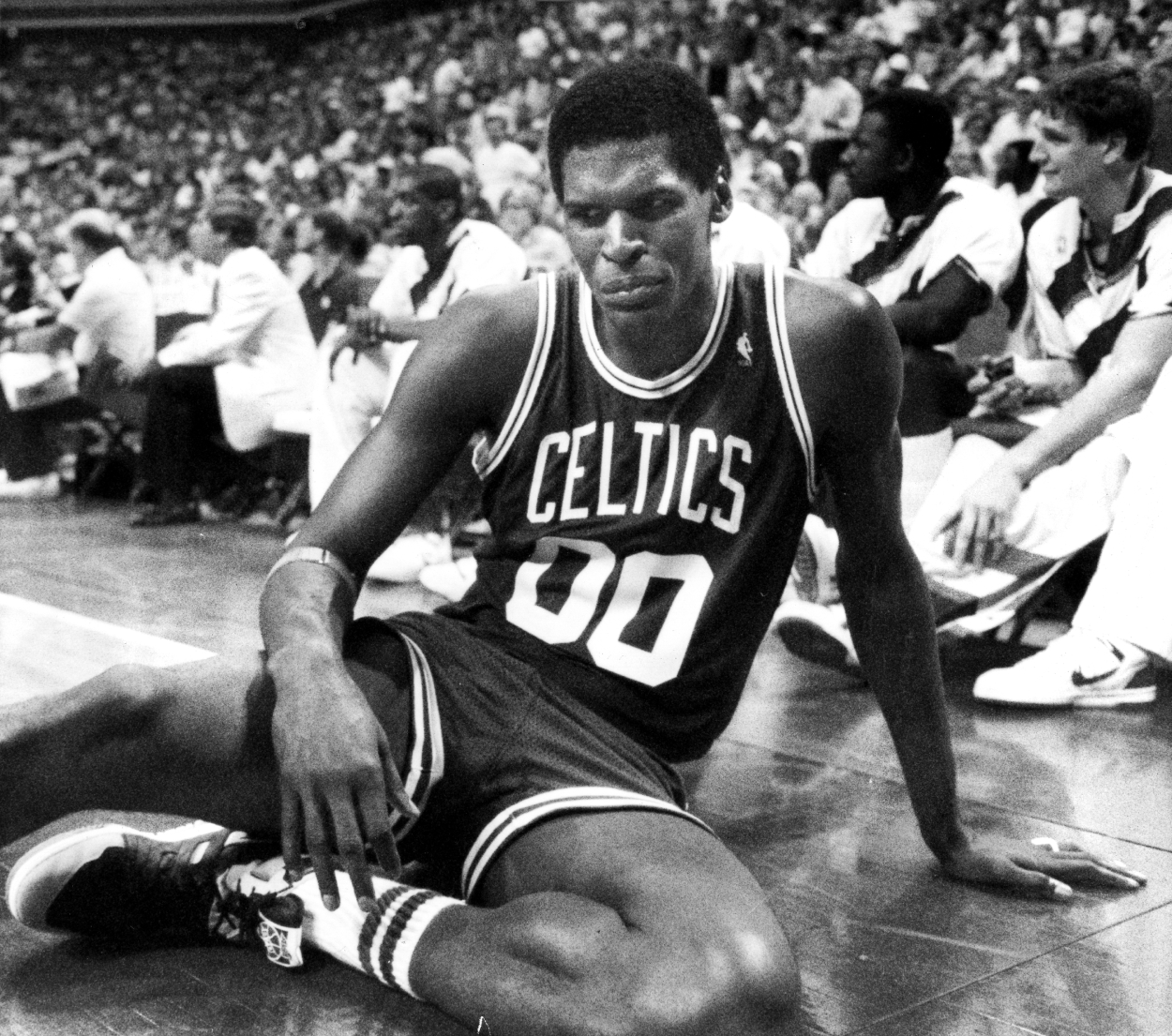 Boston Celtics' Robert Parish sits dejectedly on the floor.