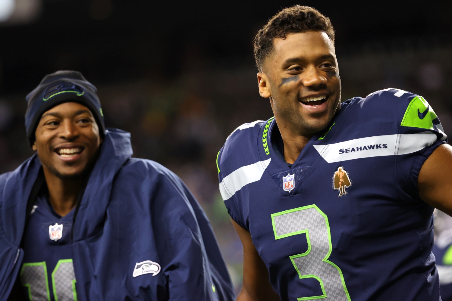 Seattle Seahawks stars Tyler Lockett and Russell Wilson celebrate a teammate scoring a touchdown.