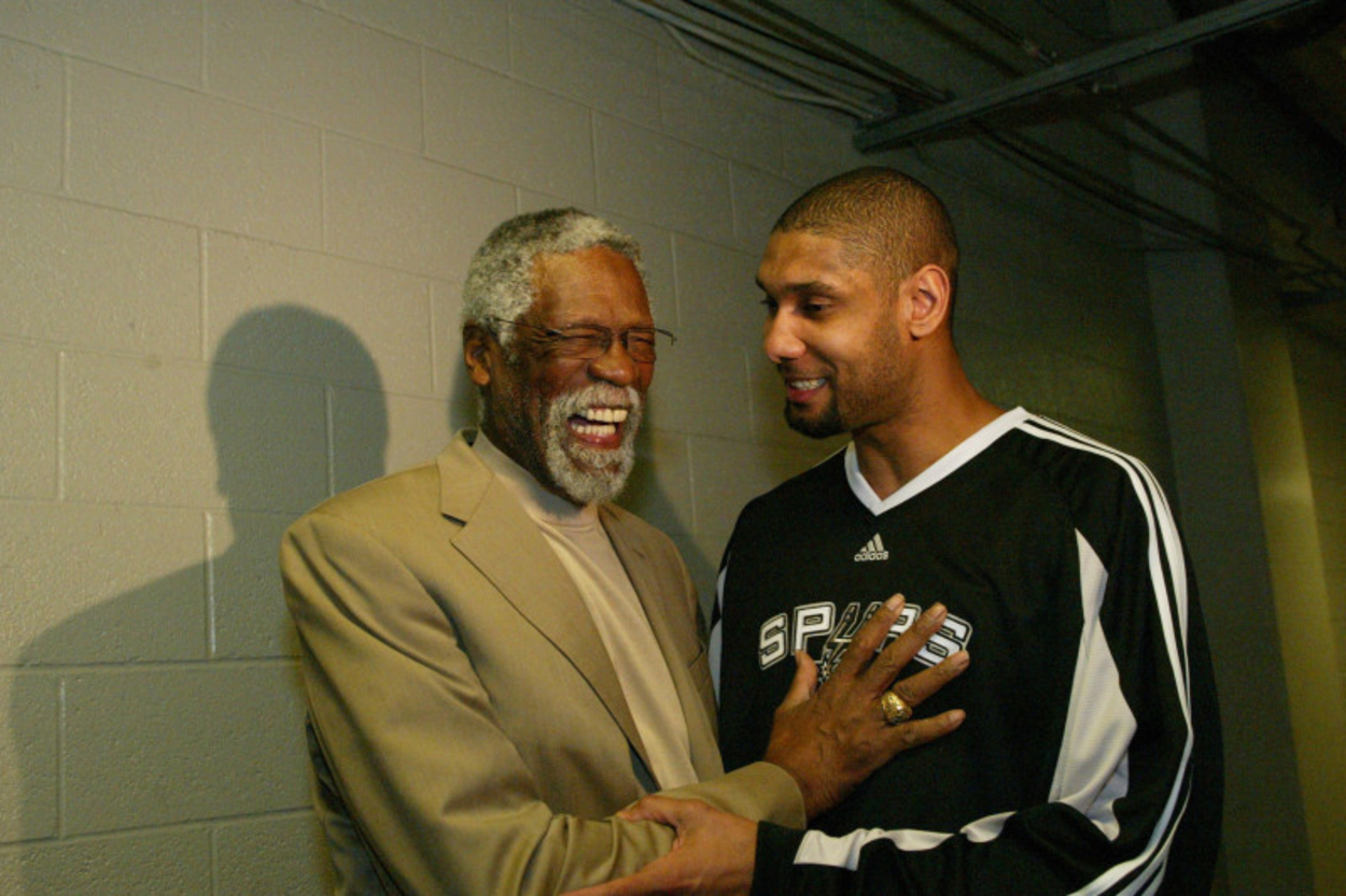 Bill Russell laughs and places his hand on TIm Duncan's chest as the two catch up in the tunnel.