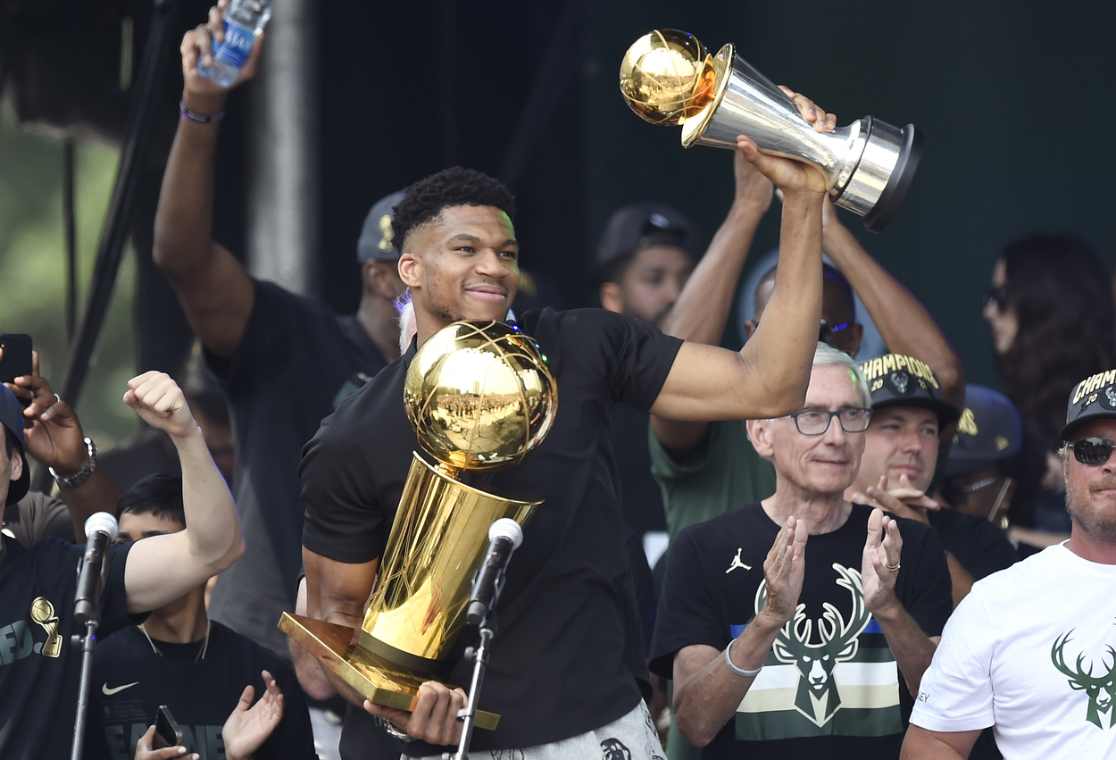 Giannis Antetokounmpo holds his two trophies up during the Milwaukee Bucks' title celebration.