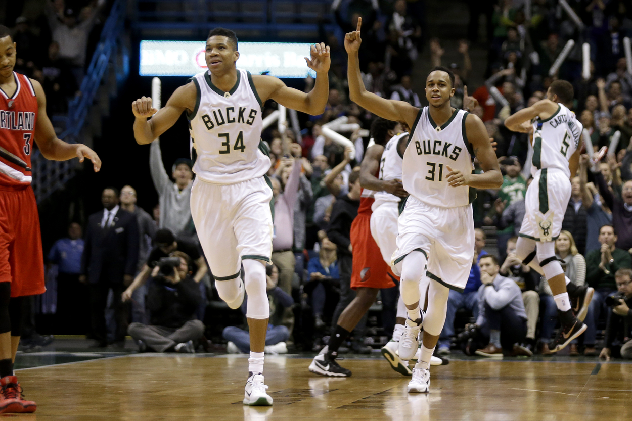 John Henson and Giannis Antetokounmpo raise their arms in celebration after a Milwaukee Bucks victory.