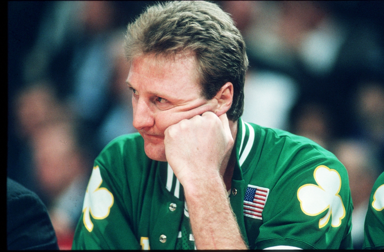 Larry Bird of the Boston Celtics sits courtside during a game.