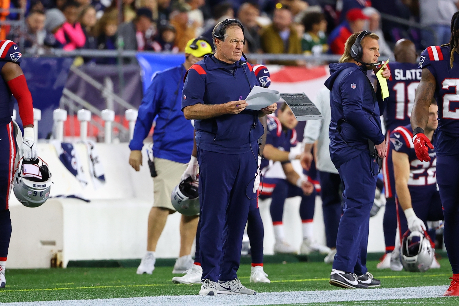 New England Patriots head coach Bill Belichick watches his team play while holding printouts of a previous series.