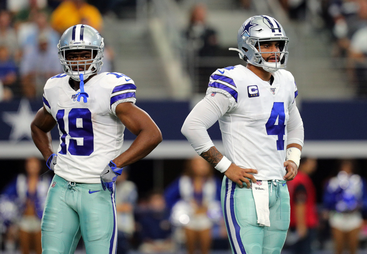 Amari Cooper #19 of the Dallas Cowboys and Dak Prescott #4 of the Dallas Cowboys stand on the field.