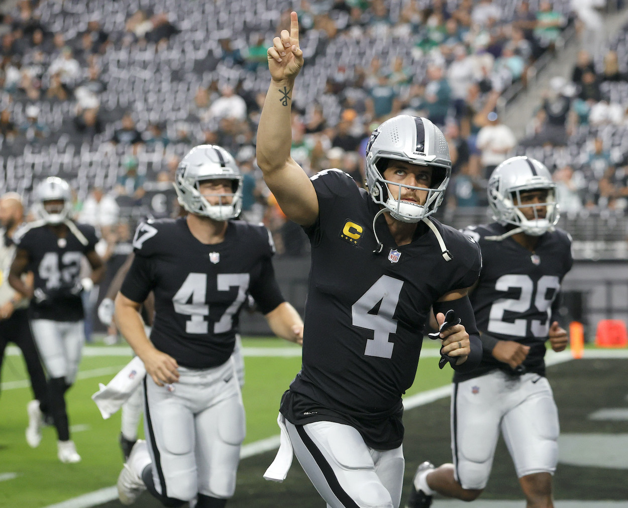 Quarterback Derek Carr of the Las Vegas Raiders, who delivered a blunt message to teammates after the Jon Gruden scandal, gestures as he leaves the field with teammates Trent Sieg and Casey Hayward Jr. after warmups before a game against the Philadelphia Eagles at Allegiant Stadium on October 24, 2021 in Las Vegas, Nevada. The Raiders defeated the Eagles 33-22.