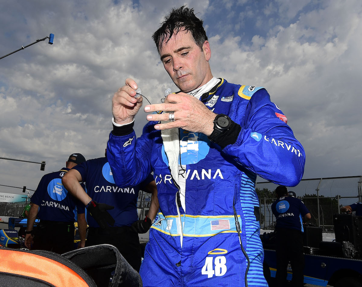 Indycar driver Jimmie Johnson takes off his ear pieces following a practice session