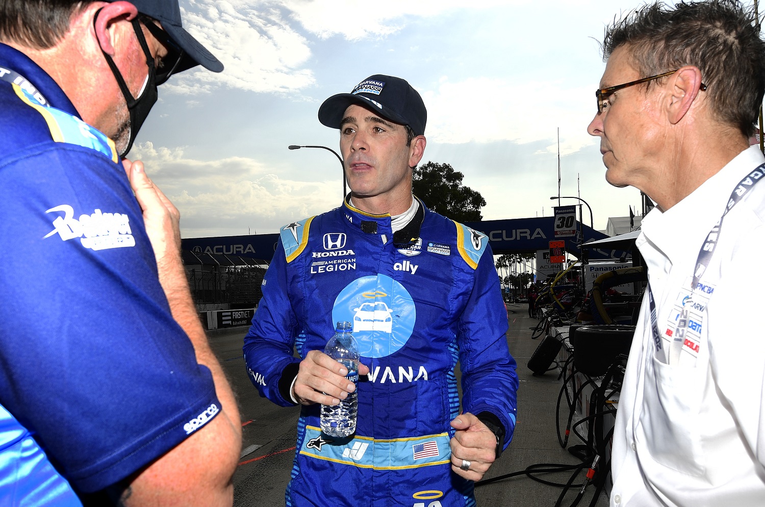 Indycar driver Jimmie Johnson, center, speaks with Scott Pruett, right, and a crew member following the opening practice session at the Grand Prix of Long Beach on Sept. 24, 2021.