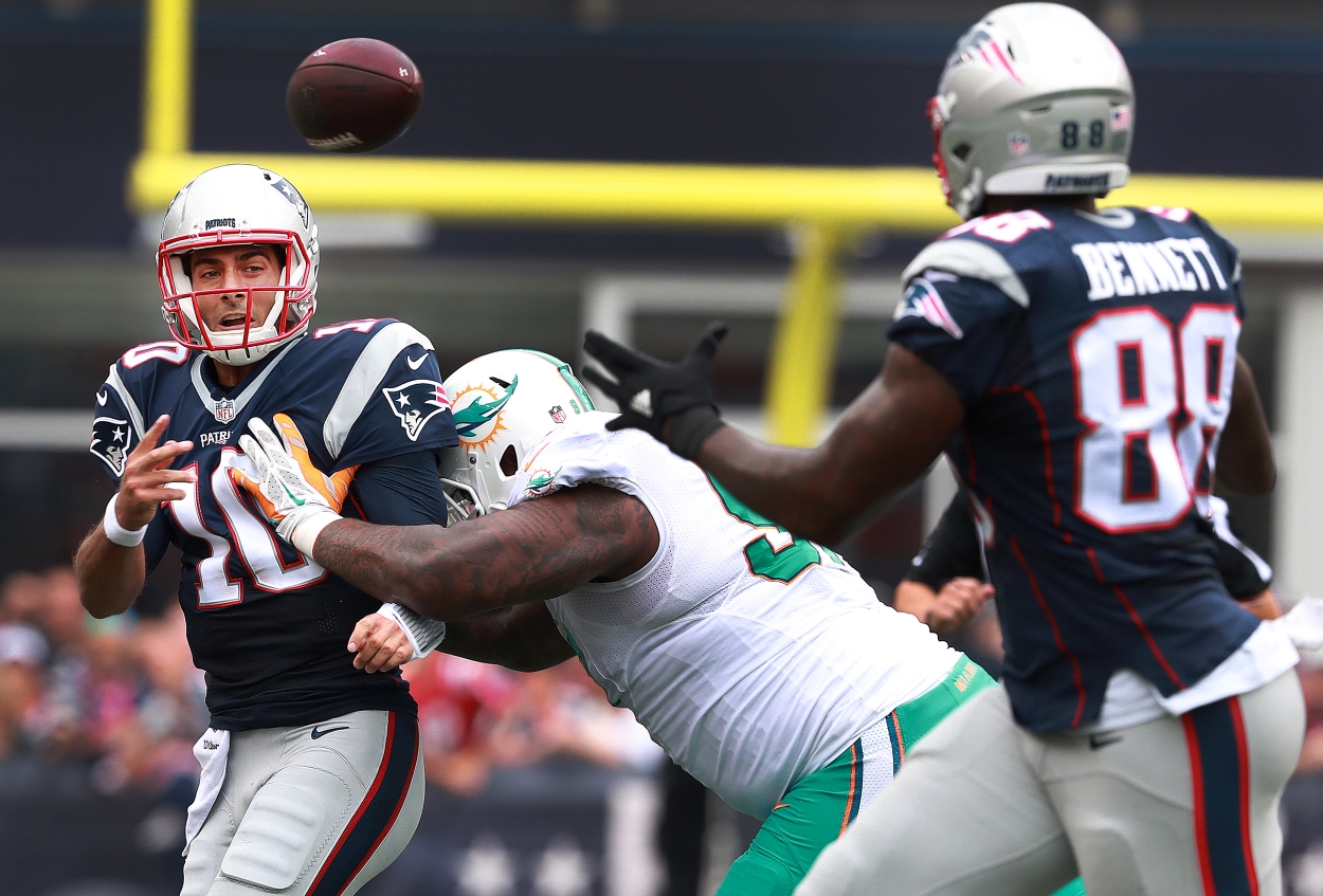 New England Patriots QB Jimmy Garoppolo attempts to get a pass away to Martellus Bennet while being hit by a Miami Dolphins defender.